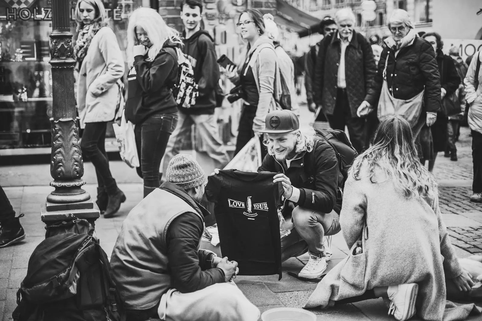 Strasseneinsatz: Menschen sitzen mit Obdachlosen auf dem Boden